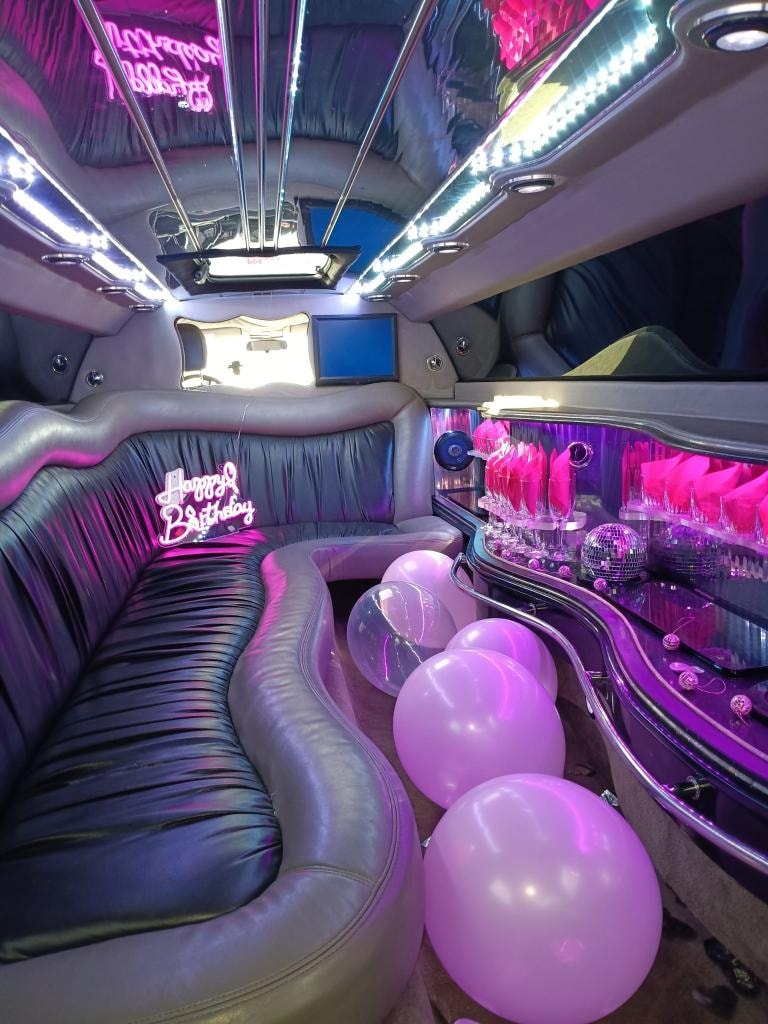 Chrysler 300 interior — birthday party setup with pink neon lighting, balloons, champagne glasses and disco balls