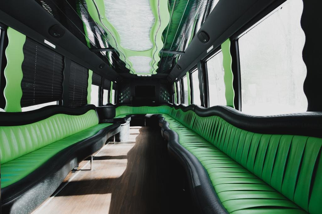 New Orleans Limo Bus interior — green and black leather seating with wavy ceiling, hardwood floor and panoramic windows
