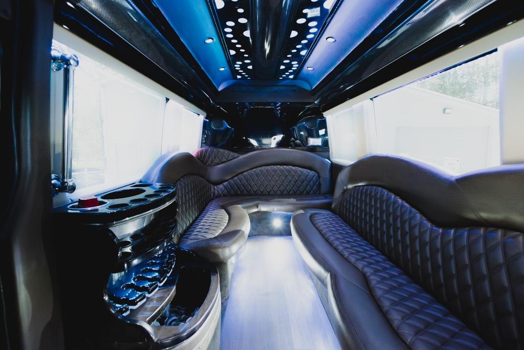 Sprinter van interior — blue ambient lighting with quilted leather seating and bar area