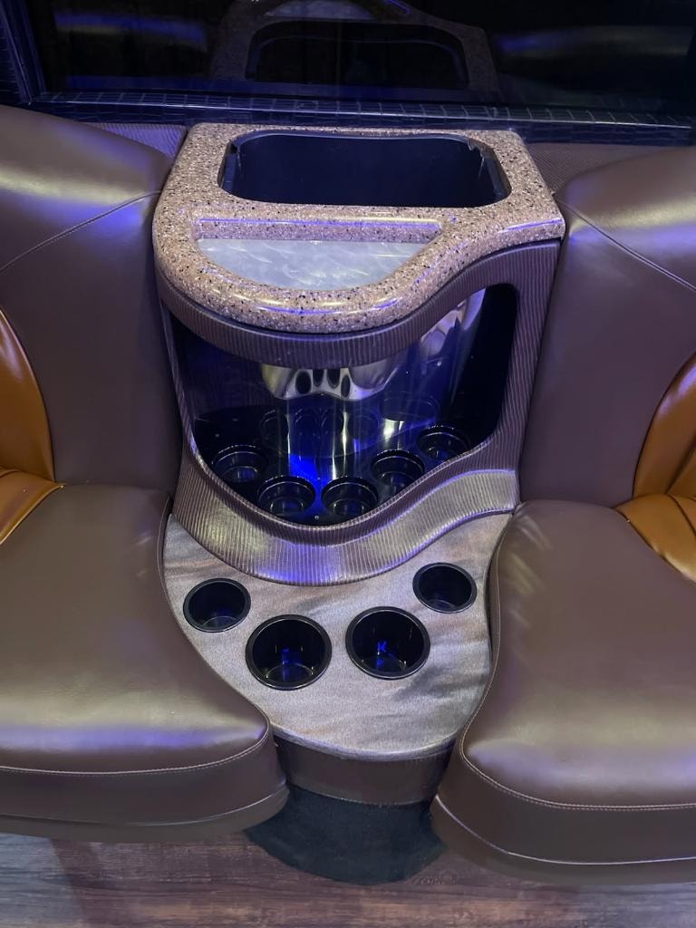 Vegas Limo Bus interior — tan leather seating with illuminated bar console and blue accent lighting